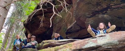 Kinder sitzen im Wald auf einem Felsen