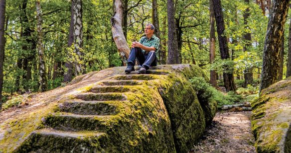 Wanderer ruht sich auf Treppenfelsen aus