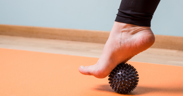 Nackter Fuß wird mit einem Massageball trainiert
