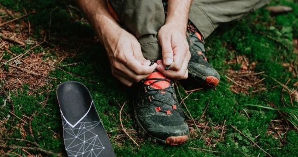 Mann bindet im Wald seine Wanderschuhe