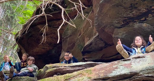 Kinder sitzen im Wald auf einem Felsen