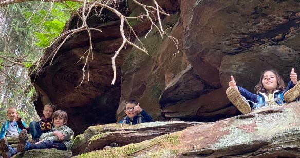 Kinder sitzen im Wald auf einem Felsen