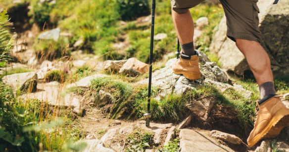 Beine eines Wanderers, der über unebenes Gelände läuft