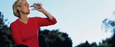 Ausreichend trinken Frau trinkt auf einer Wiese Wasser aus einer Flasche
