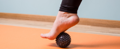 Faszientraining Nackter Fuß wird mit einem Massageball trainiert