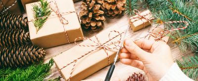 Selbstgemachte Last-Minute-Geschenke für Weihnachten Geschenke, die mit Paackpapier eingepackt sind, im Hintergrund sind Tannenzapfen und Zweige zu sehen