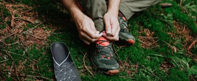 Mann bindet im Wald seine Wanderschuhe