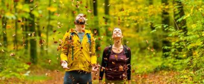 Mann und Frau werfen Blätter hoch im Wald Mann und Frau werfen Blätter hoch im Wald