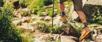 Beine eines Wanderers, der über unebenes Gelände läuft