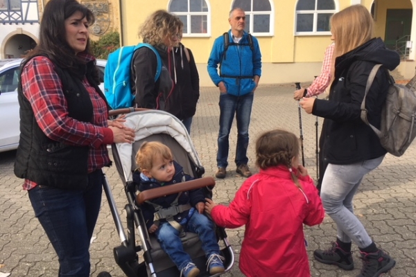Familie mit Kinderwagen und Kind trifft sich auf einem Parkplatz