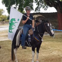 Antje Elzer sitzt auf einem Pferd und hält eine Fahne in der Hand